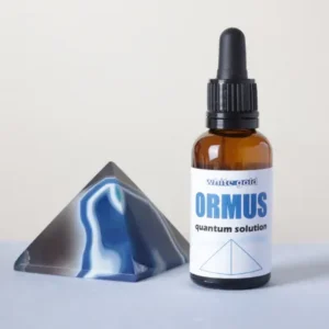 ¿Qué es el Ormus?Frasco de White Gold Ormus Quantum Solution junto a una pirámide de ágata azul y gris sobre un fondo neutro, ilustrando qué es el Ormus.